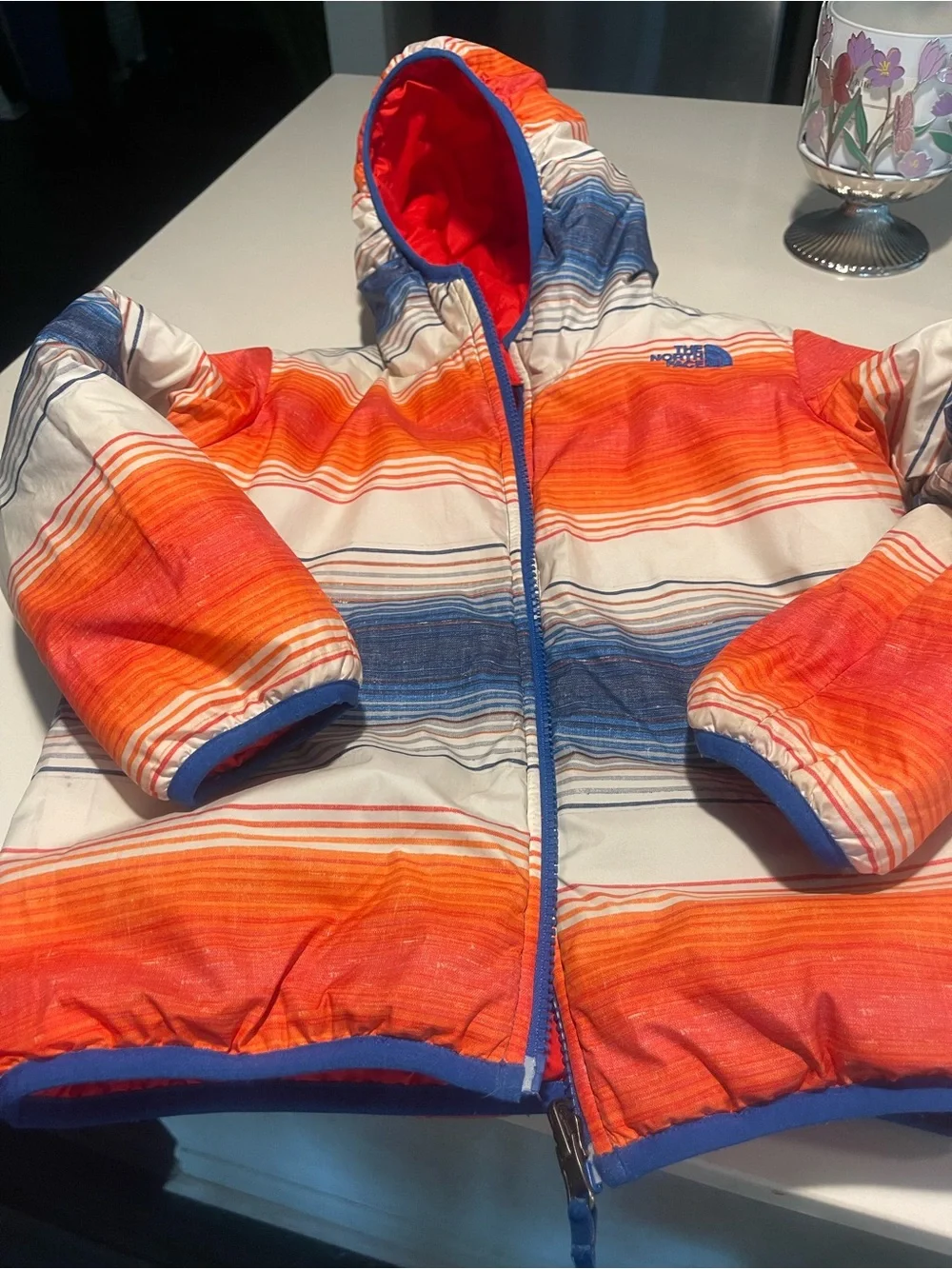 The North Face reversible Solid Red or Vibrant Striped side Puffer Jacket.